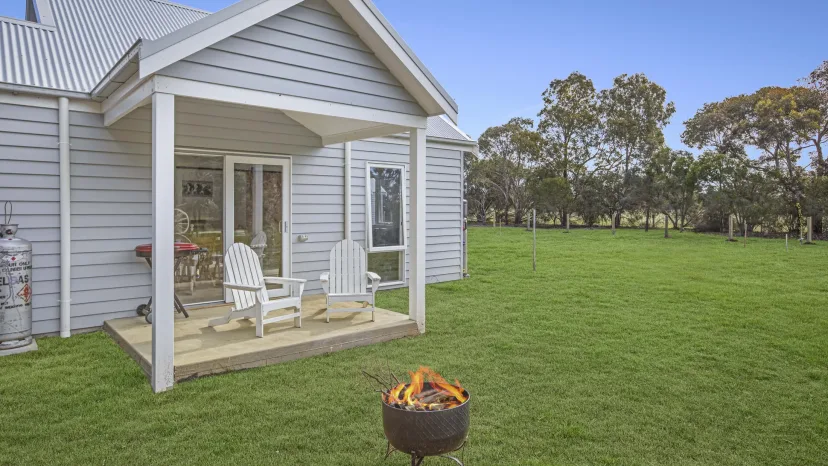 Sage Cottage verandah with two chairs and an open fire pit on the lawn