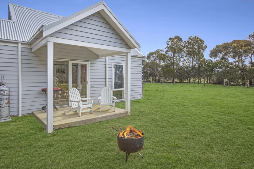 Sage Cottage verandah with two chairs and an open fire pit on the lawn