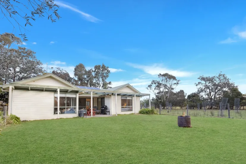 Woongara Cottage seen across the paddock, with the farm gate in the foreground