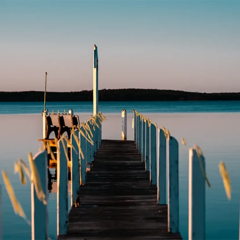 A timber jetty reaching out over still water at dusk